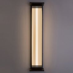 a wall light that is mounted on the side of a wall with dim lighting in front of it