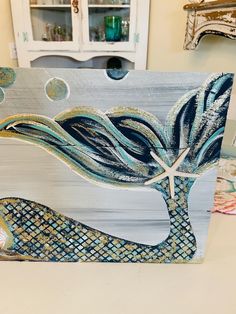 a wooden sign with a painting of a tree and starfish on it's side