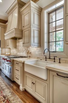 a large kitchen with white cabinets and wooden flooring, along with a rug on the floor