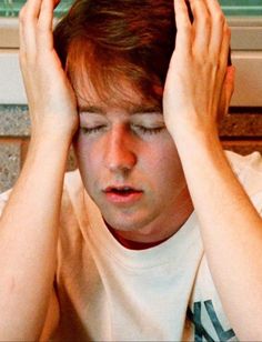 a young man holding his hands to his head