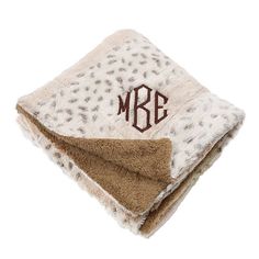 the monogrammed leopard print blanket is on top of a brown and white towel