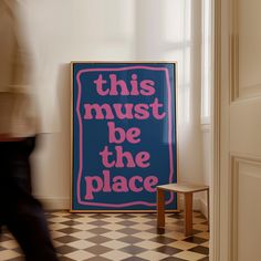 this must be the place poster on wall next to small stool in room with black and white checkered floor