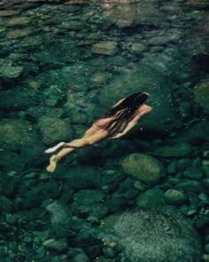 a woman floating in the water on top of rocks