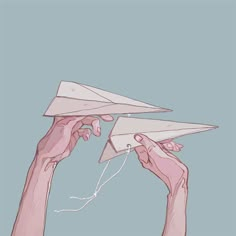 two hands holding up a paper airplane in the air with string attached to it's wings