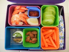 a purple lunch box filled with different types of vegetables and fruits, including carrots, celery, apples, almonds, and pickles