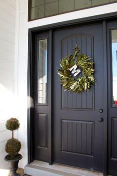 a black front door with a wreath on it