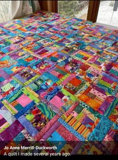 a colorful quilt is on the floor in front of a window