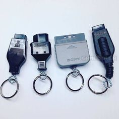 four different types of electronic gadgets are lined up on a white surface with keychains