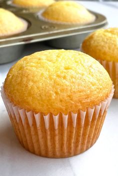 two muffins sitting on top of a table next to a pan of muffins