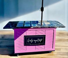 a pink and blue ice cream cart sitting on top of a wooden floor