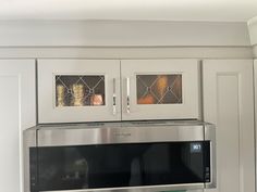 a microwave built into the side of a cabinet in a kitchen with white cabinets and stainless steel appliances