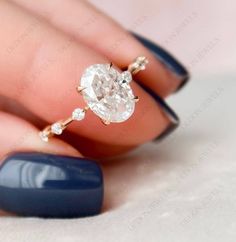 a woman's hand holding a ring with an oval shaped diamond in the middle