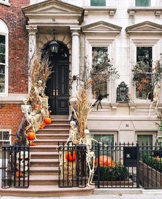 halloween decorations on the front steps of a house with pumpkins and skeletons in them