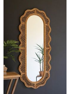 a mirror that is on the wall next to a table with a potted plant