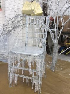 a chair covered in ice and icicles next to a tree with no leaves on it