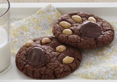 two chocolate cookies with peanut butter on top and a glass of milk next to it