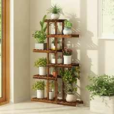 a wooden shelf filled with potted plants next to a window