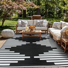 a black and white rug on a wooden deck with chairs, couches and coffee table