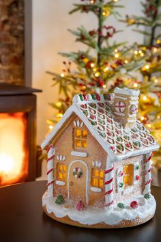 a small gingerbread house sitting on top of a table next to a christmas tree