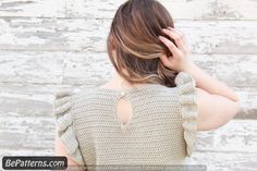 the back of a woman's sweater, with her hands on her head and one hand in her hair