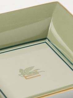 a green and gold serving tray with a bird on the bottom, sitting on a white surface