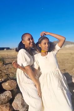 two women standing next to each other near rocks