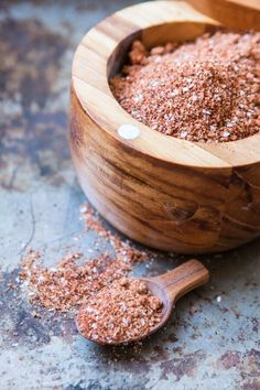 a wooden bowl filled with ground cinnamon on top of a table next to a spoon