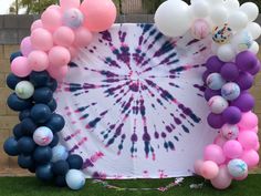 a tie - dyed backdrop with balloons and streamers in the shape of a circle