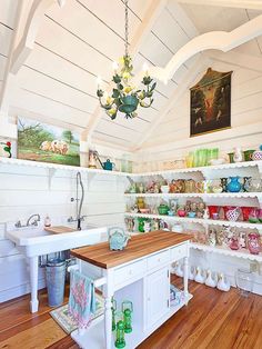 a kitchen with white walls and wooden flooring next to shelves filled with glassware