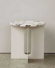 a white table sitting on top of a floor next to a wall