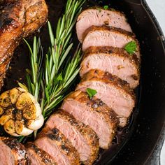 sliced meat and vegetables in a skillet on a table with utensils for garnishes