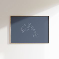 a framed photograph of a dolphin jumping out of the water in front of a white wall