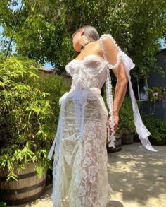 a woman in a white dress is standing outside