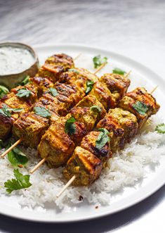 a white plate topped with meat skewers and rice