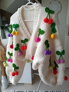 a white sweater with pom - poms hanging from it's sides on a rack