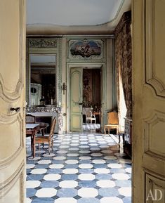 an open door leading to a living room with white and blue tiles on the floor