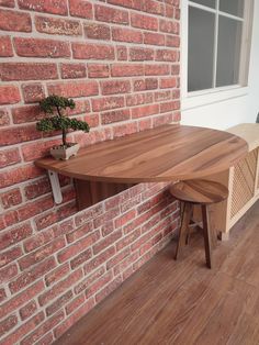 a wooden table sitting on top of a hard wood floor next to a brick wall