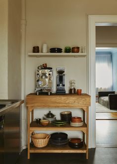 a wooden shelf filled with bowls and plates on top of a kitchen counter next to a coffee maker