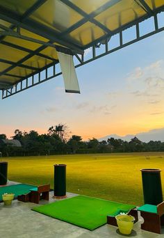 the sun is setting over a golf course with green grass and yellow cups on it