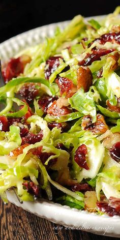 a salad with bacon and lettuce on a white plate sitting on a wooden table