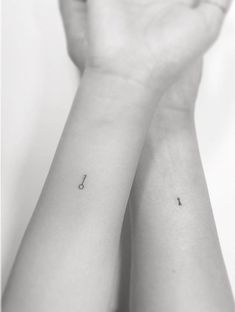 two hands holding each other with small tattoos on their wrist and one has an arrow in the middle