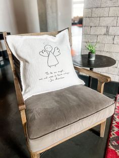 a chair with a pillow sitting on top of it next to a table and potted plant