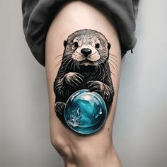 an animal tattoo on the leg of a woman's thigh, with a blue ball in it