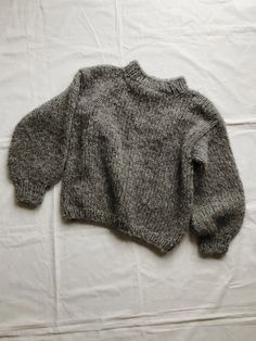 a gray sweater laying on top of a white sheet