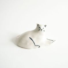 a white cat figurine sitting on the ground