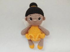 a small crocheted doll with black hair and brown eyes sitting on a white surface