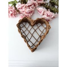 a heart shaped basket sitting on top of a table next to pink flowers and greenery