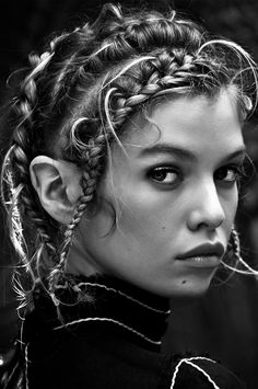 a woman with braids in her hair looking at the camera, black and white photo