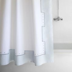 the shower curtain is white and has blue trim on it, along with a bathtub in the background