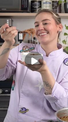 a woman in a kitchen holding a bowl and spoon